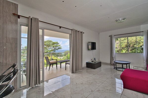 A hotel room with a balcony, a bed, a TV, and a small table.