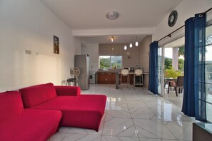 A modern living room with a red sofa, a kitchen area, and a dining space with a view.