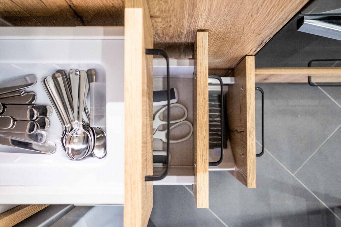 A kitchen drawer with utensils and a kettle.