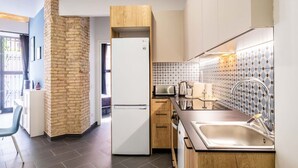 A modern kitchen with a refrigerator, wooden cabinets, a tiled backsplash, and a sink.