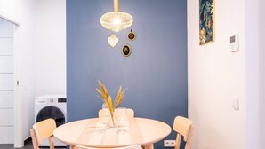 Ein Essbereich mit rundem Tisch, Stühlen, einer Pendelleuchte und einer an der Wand befestigten Waschmaschine.