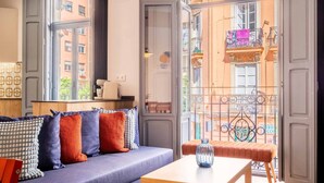 A cozy room with a sofa, a small table, and a view of a balcony with a railing. - Beautiful Suite with Private Terrace (Valencia)