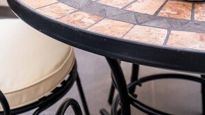 A round table with a tiled edge, two white plates, a white mug, and a beige cushion. - Beautiful Suite with Private Terrace (Valencia)