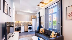 A compact living space with a kitchenette, a sofa, a dining table, and a large window. - Classy Studio Apartment with Unique Design (Valencia)