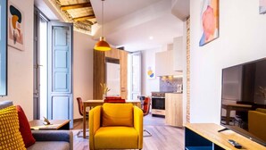 Uma sala de estar moderna com um sofá, uma poltrona amarela e um espaço de refeições com mesa e cadeiras.