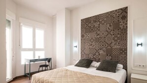 Quarto com cama, escrivaninha e cabeceira estampada.