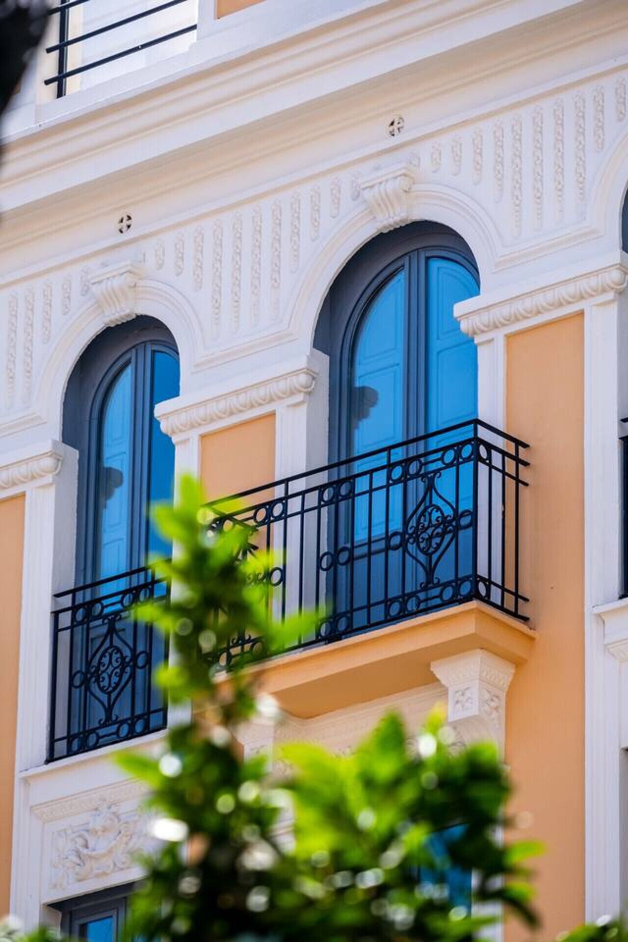 A building with three large arched windows and a balcony with ornate black railings.