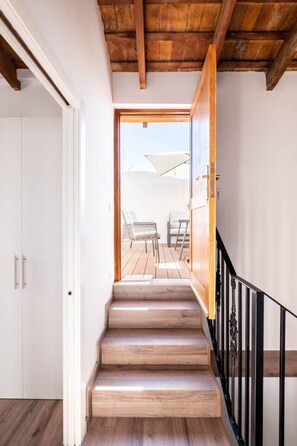 A wooden staircase leading to an outdoor patio with a view of the sky and a white umbrella.
