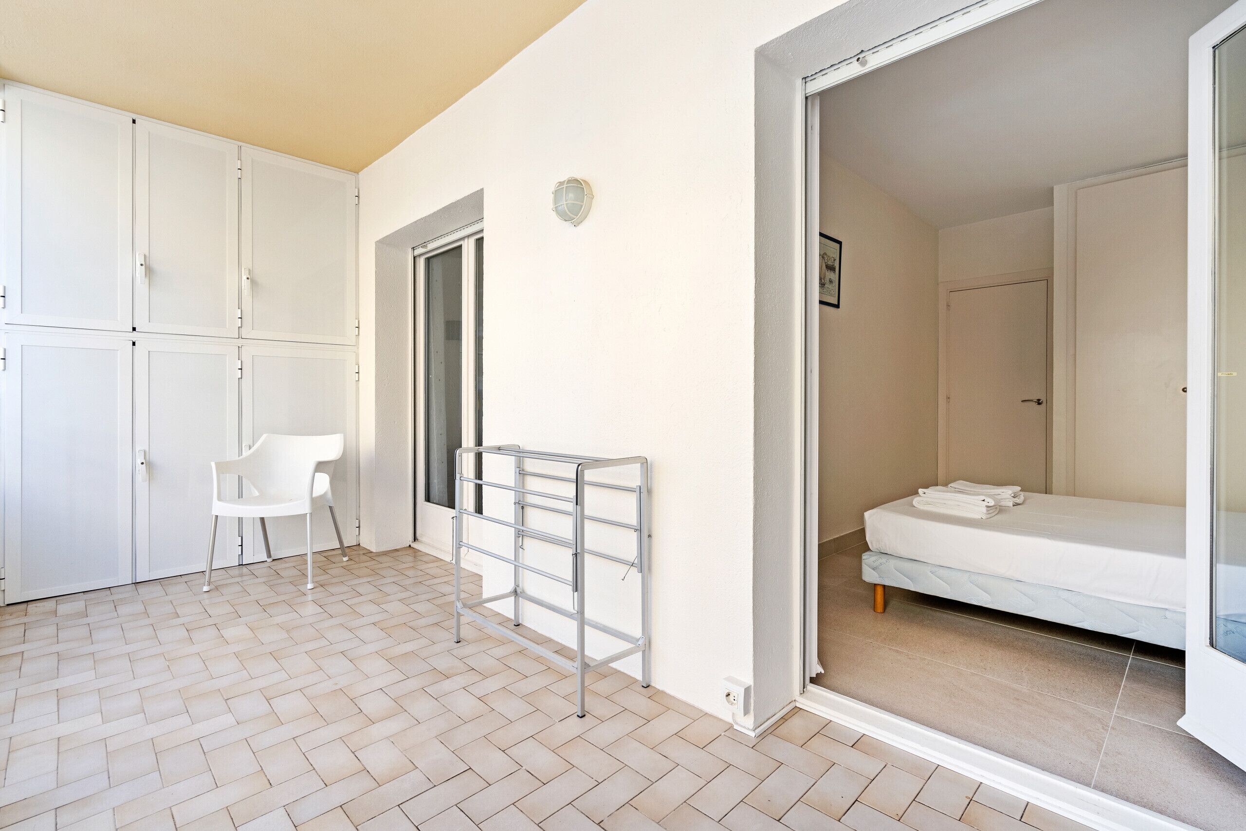 A bedroom with a bed, a chair, and a wardrobe.
