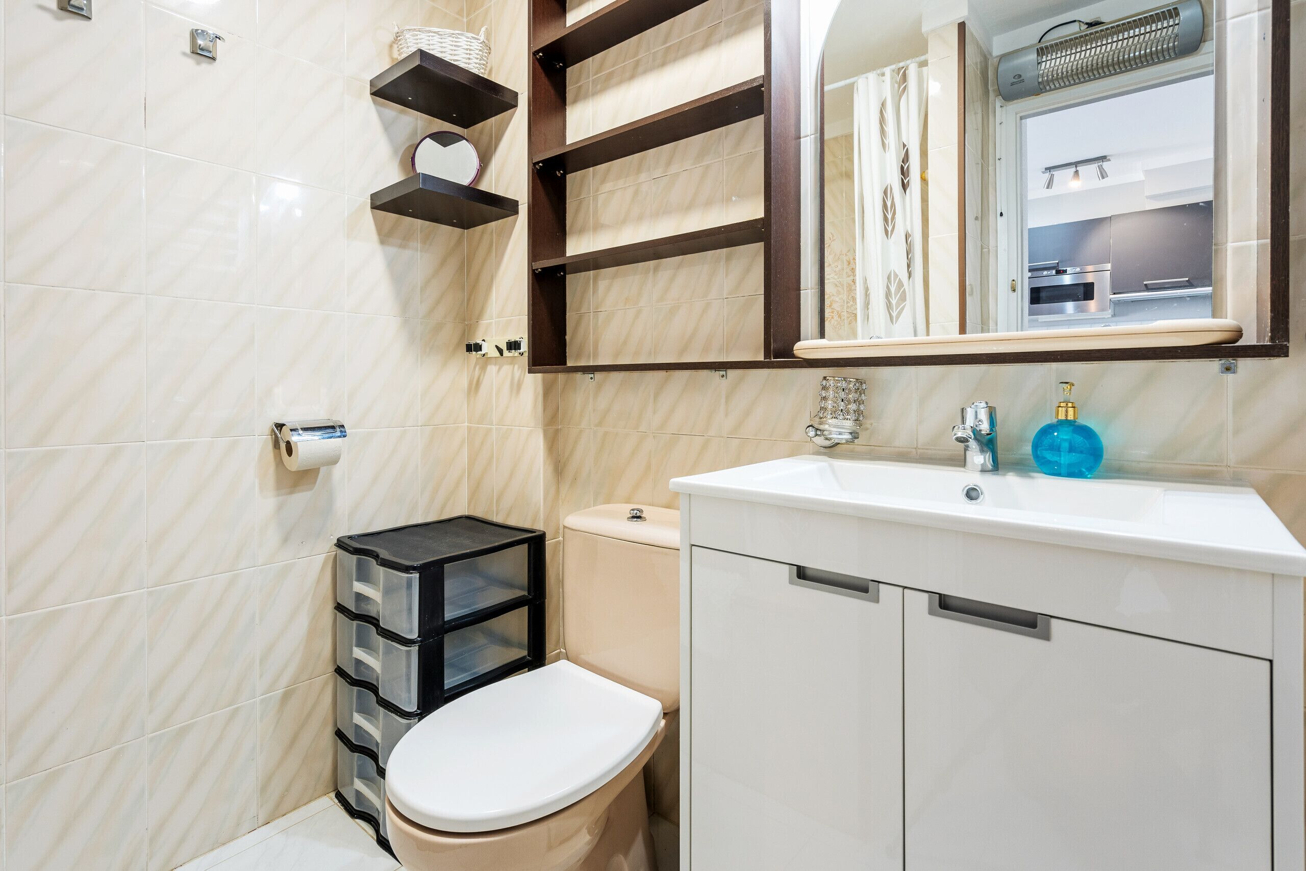 Een moderne badkamer met toilet, opbergruimte en een wastafel met spiegel erboven.