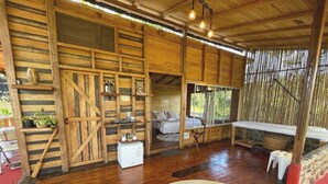 Een rustiek houten blokhutinterieur met een bed, zithoek en een kleine kitchenette.