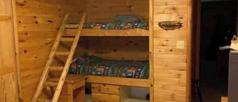Een houten kamer met stapelbedden, een plafondventilator en een ladder.