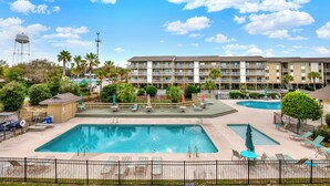 A hotel with a swimming pool, outdoor seating, and a water tower in the background.