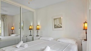A hotel room with two beds, a large mirror, bedside lamps, and a framed picture on the wall. - Garden Pool Apartment in Mijas by Costarentals - Ref 209 (Las Lagunas de Mijas)