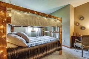 Un lit superposé avec une tête de lit en bois, une table de chevet et une chaise.