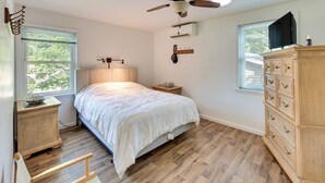 A bedroom with a bed, wooden dresser, nightstand, and ceiling fan. - Quaint Elysburg Cottage: Walk to Knoebels Resort! (Elysburg)