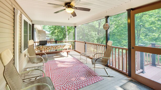 A covered porch with a ceiling fan, a table with chairs, and a view of the surrounding trees. - Quaint Elysburg Cottage: Walk to Knoebels Resort! (Elysburg)