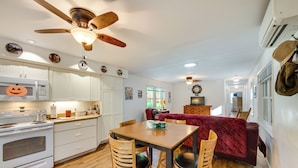 A kitchen with white cabinets, a wooden dining table, and a red sofa. - Quaint Elysburg Cottage: Walk to Knoebels Resort! (Elysburg)