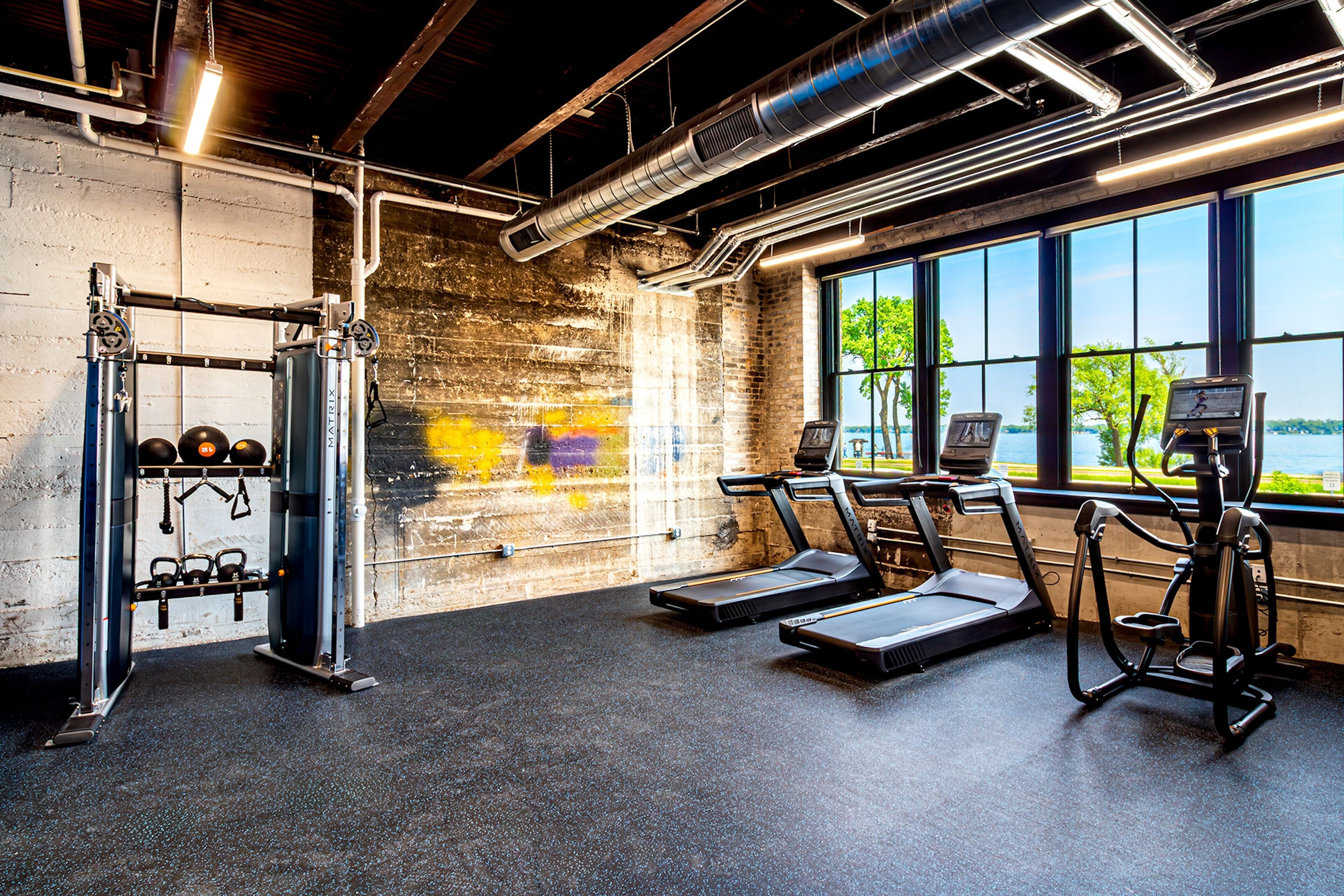 A gym with treadmills, a weight machine, and a view of a lake.