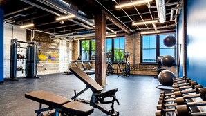 A gym with exercise equipment, large windows, and a view of trees. - The Saddlery Madison Downtown (Madison)