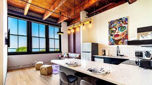 A modern kitchen with a large island, bar stools, and a view of the outdoors. - The Saddlery Madison Downtown (Madison)