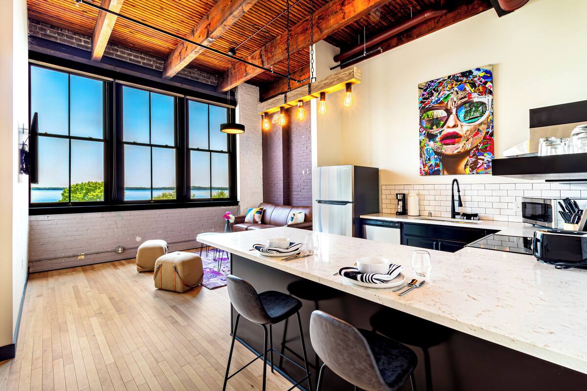 A modern kitchen with a large island, bar stools, and a view of the outdoors.