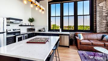 Una cocina moderna con una isla grande, un comedor con sofá de cuero y un ventanal con vistas a la ciudad.