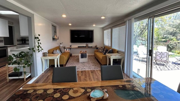 A modern living room with a large TV, comfortable seating, and a view of the outdoors. - Dream Catcher Getaway (Clearlake Oaks)
