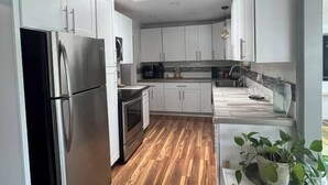 A modern kitchen with white cabinets, stainless steel appliances, and a wooden floor. - Dream Catcher Getaway (Clearlake Oaks)