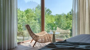 A bedroom with a large window, a wicker chair, and a small table with a glass. - VILA NICOL TIRELI premium and private Villa in Istria for your family vacation (Boljevići)