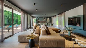 A modern living room with a large sofa, a dining area, and a kitchen in the background. - VILA NICOL TIRELI premium and private Villa in Istria for your family vacation (Boljevići)