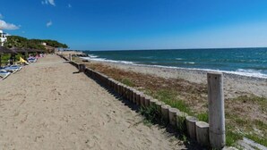 A beach with a wooden walkway, beach chairs, and umbrellas. - Vacances EN Corse (San-Nicolao)