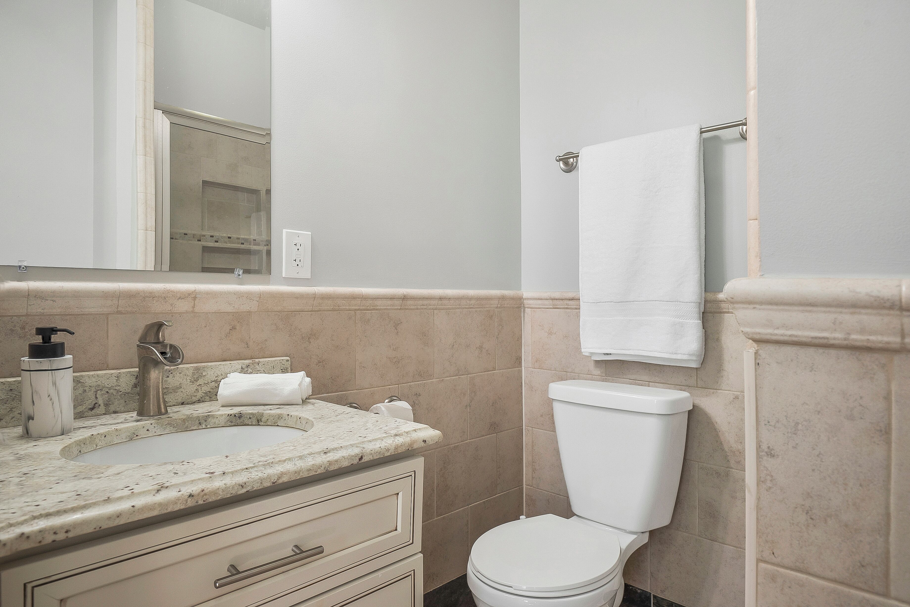 A bathroom with a sink, mirror, toilet, and towel rack.