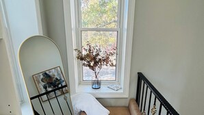 Un escalier agrémenté d’un banc rembourré, d’un miroir, d’un vase contenant des fleurs séchées et d’un tapis à motifs.