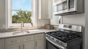 Une cuisine avec des meubles blancs, une cuisinière en acier inoxydable et un four à micro-ondes.
