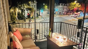 Un balcon avec un canapé et une petite table sur laquelle se trouvent une bouteille et des verres.