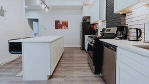 Een moderne keuken met witte kasten, een centraal eiland, een fornuis en een vaatwasser.