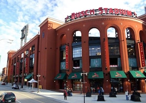 Un estadio con señalización 'BUSCH STADIUM', múltiples entradas y zonas de asientos al aire libre.