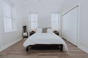 A bedroom with a bed, two bedside tables with lamps, a wardrobe, and a mirror.