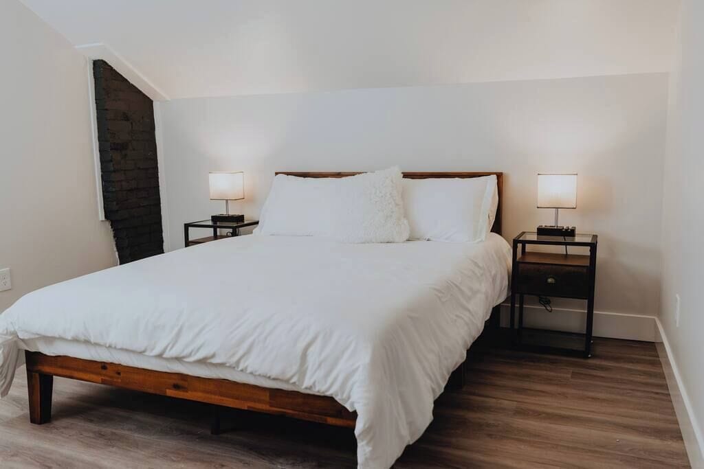 Ein Schlafzimmer mit einem hölzernen Bett, zwei Nachttischen und einer Ziegelwand.