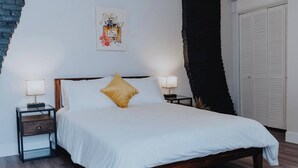 Een slaapkamer met een bed, nachtkastjes, een wanddecoratie en een kledingkast.