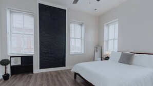 Een slaapkamer met een bed, een accentmuur in het zwart en een potplant.
