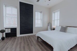 Un dormitorio con una cama, una pared de acento negra y una planta en maceta.