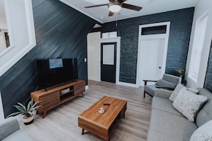 A modern living room with a TV, wooden coffee table, and grey sofa.