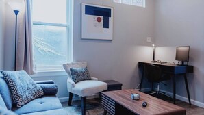 Ein modernes Wohnzimmer mit einer Couch, einem Sessel, einem Schreibtisch und einem Couchtisch.
