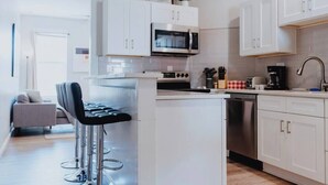 Eine moderne Küche mit weißen Schränken, Edelstahlgeräten und einer Bar mit Hockern.