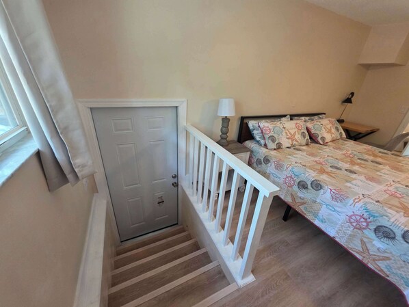 A bedroom with a bed, a nightstand, a lamp, a window with curtains, and a door. - Life at the lake Summ (Inverness)