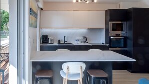 A modern kitchen with a central island, bar stools, and built-in appliances.