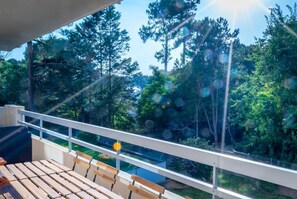 Una terraza de madera con baranda blanca que da a un área boscosa.
