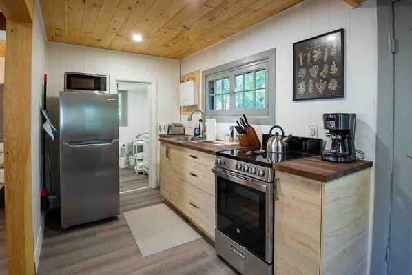A modern kitchen with stainless steel appliances, wooden cabinets, and a window providing natural light.
